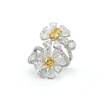 This 18K White Gold ring features a floral-inspired design with two oval-cut fancy yellow diamonds, expertly cut in a brilliant style. These radiant gems are accented by white diamond "petals"; creating a stunning contrast and adding to the ring's overall charm and opulence. A true statement piece for any special occasion!