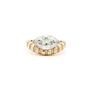 This 18K Yellow Gold ring showcases a Marquise centre stone set on a bold band, decorated with sparkling diamonds. Its exquisite craftsmanship and sophisticated design make it the perfect statement piece for any look!