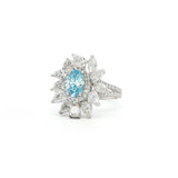 This 18K White Gold Ring showcases an exquisite floral design with a captivating oval-cut blue diamond centre, framed with white diamond "petals". A timeless embodiment of luxury and sophistication, perfect for making a statement!