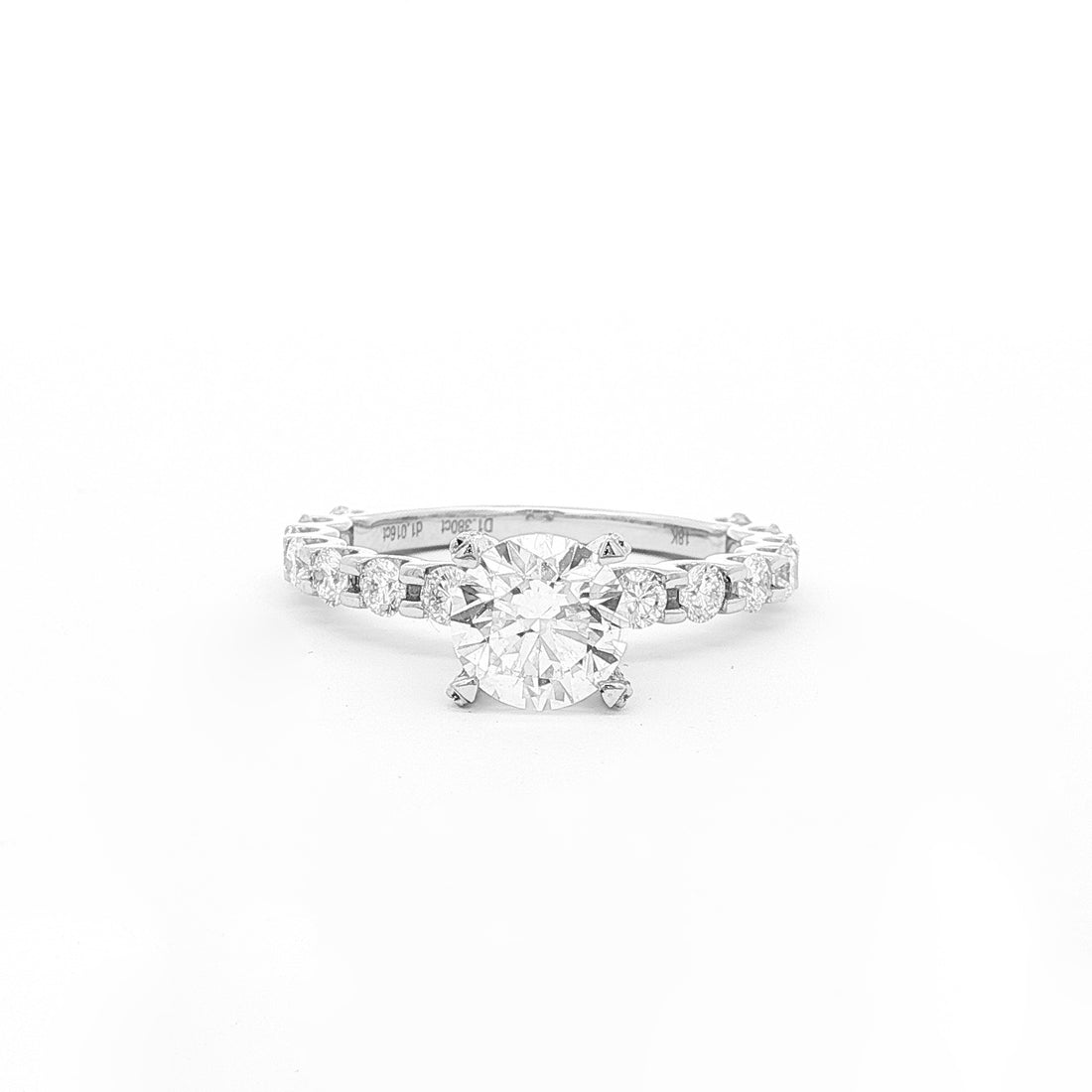 This 18K White Gold ring features a classic round-cut centre, accentuated by round sidestones along the band. This timeless design offers the perfect blend of elegance and sophistication, making it the perfect choice for an engagement ring!