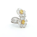 This 18K White Gold ring features a floral-inspired design with two oval-cut fancy yellow diamonds, expertly cut in a brilliant style. These radiant gems are accented by white diamond 