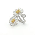 This 18K White Gold ring features a floral-inspired design with two oval-cut fancy yellow diamonds, expertly cut in a brilliant style. These radiant gems are accented by white diamond 