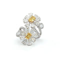 This 18K White Gold ring features a floral-inspired design with two oval-cut fancy yellow diamonds, expertly cut in a brilliant style. These radiant gems are accented by white diamond 