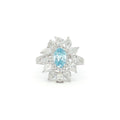 This 18K White Gold Ring showcases an exquisite floral design with a captivating oval-cut blue diamond centre, framed with white diamond 