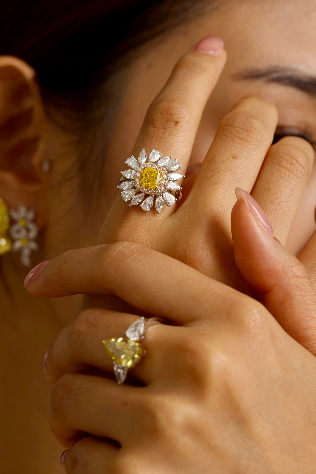 The sunflower-inspired Lumine ring is crafted in 18K tri-color gold (White, Yellow, and Rose Gold). At the centre is a fancy yellow cushion-cut diamond set in Yellow Gold. Surrounding it is a halo of pink diamonds set in Rose Gold. Completing the bloom are "petals" of white diamond set in White Gold. The result is a bold and captivating dual-tone statement piece, perfect for adding a touch of glamour to any evening look.