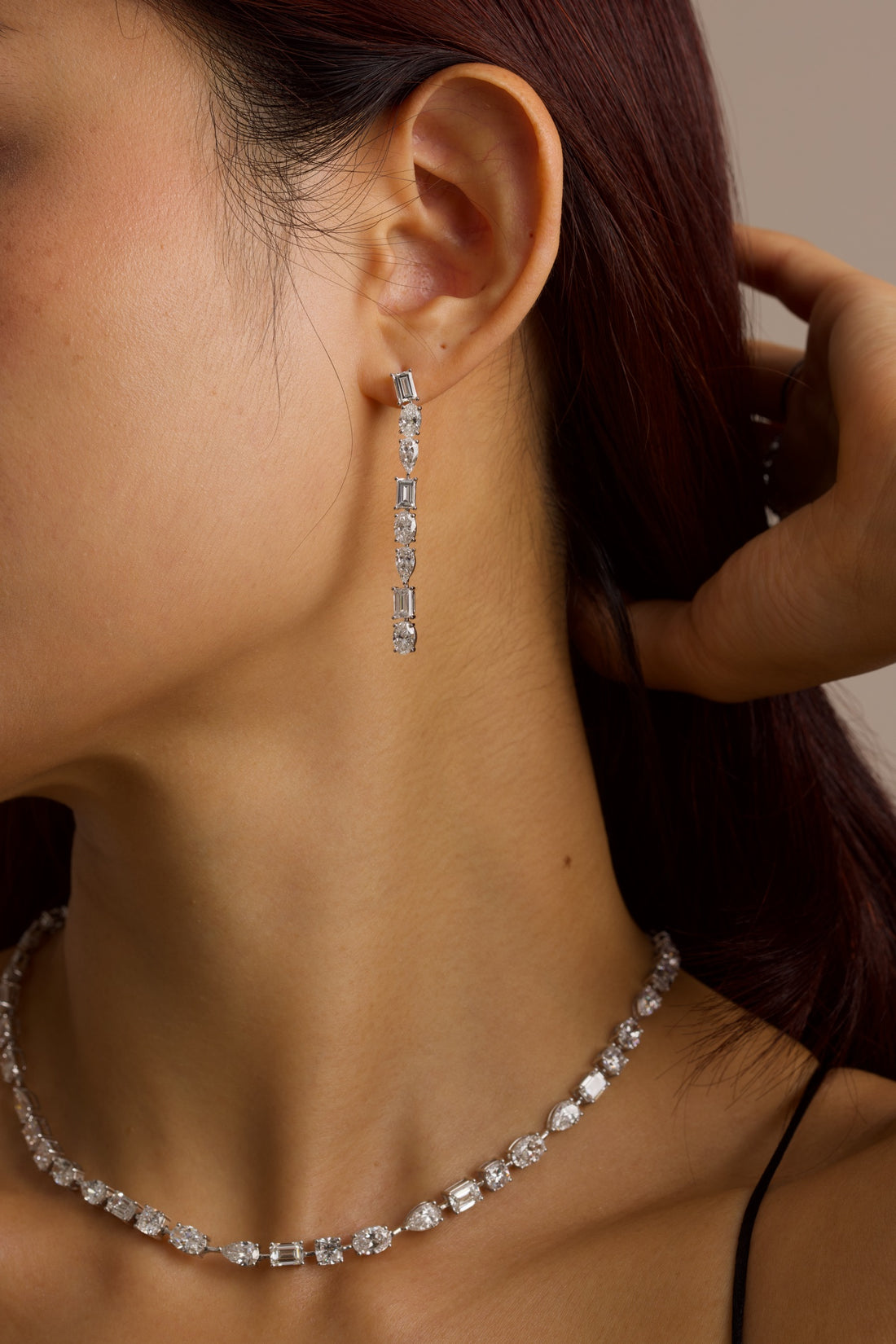 Close-up of a person wearing a diamond necklace and drop earrings.