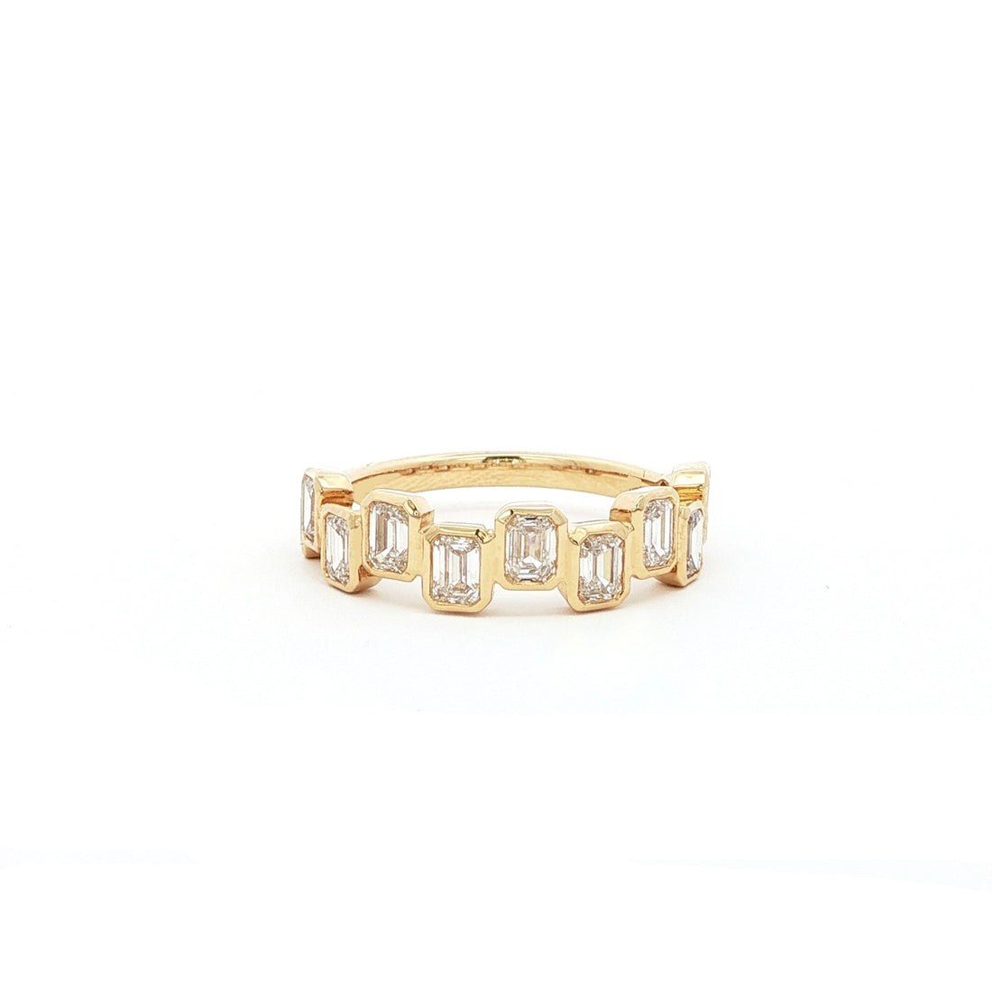 18K Yellow Gold half-eternity ring featuring bezel-set emeralds in a playful high-low pattern. A modern twist on the classic eternity band, designed for effortless sparkle and everyday wear.