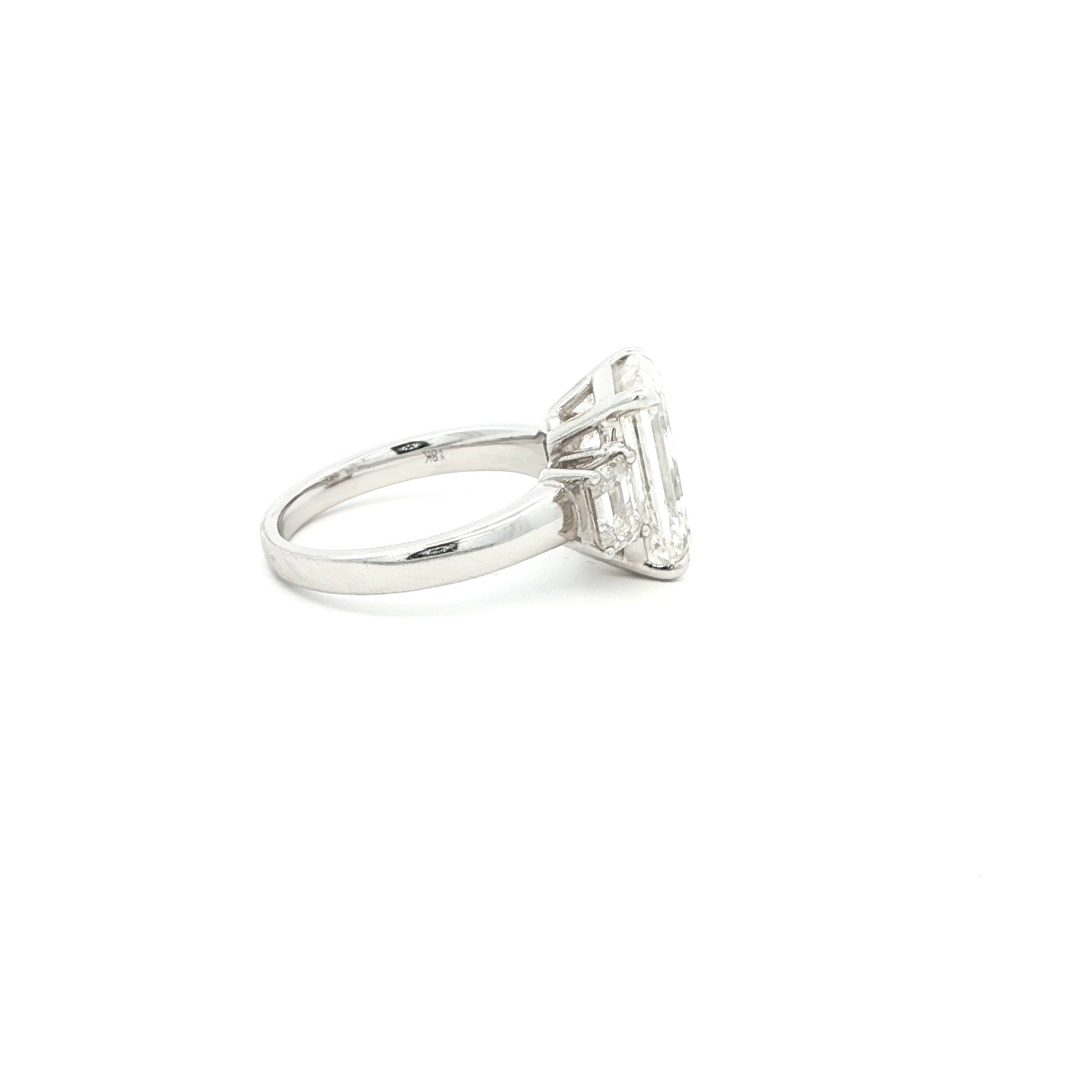Three-stone ring featuring a lab-grown emerald cut center diamond with two emerald side stones, set in a classic design in 18k gold.